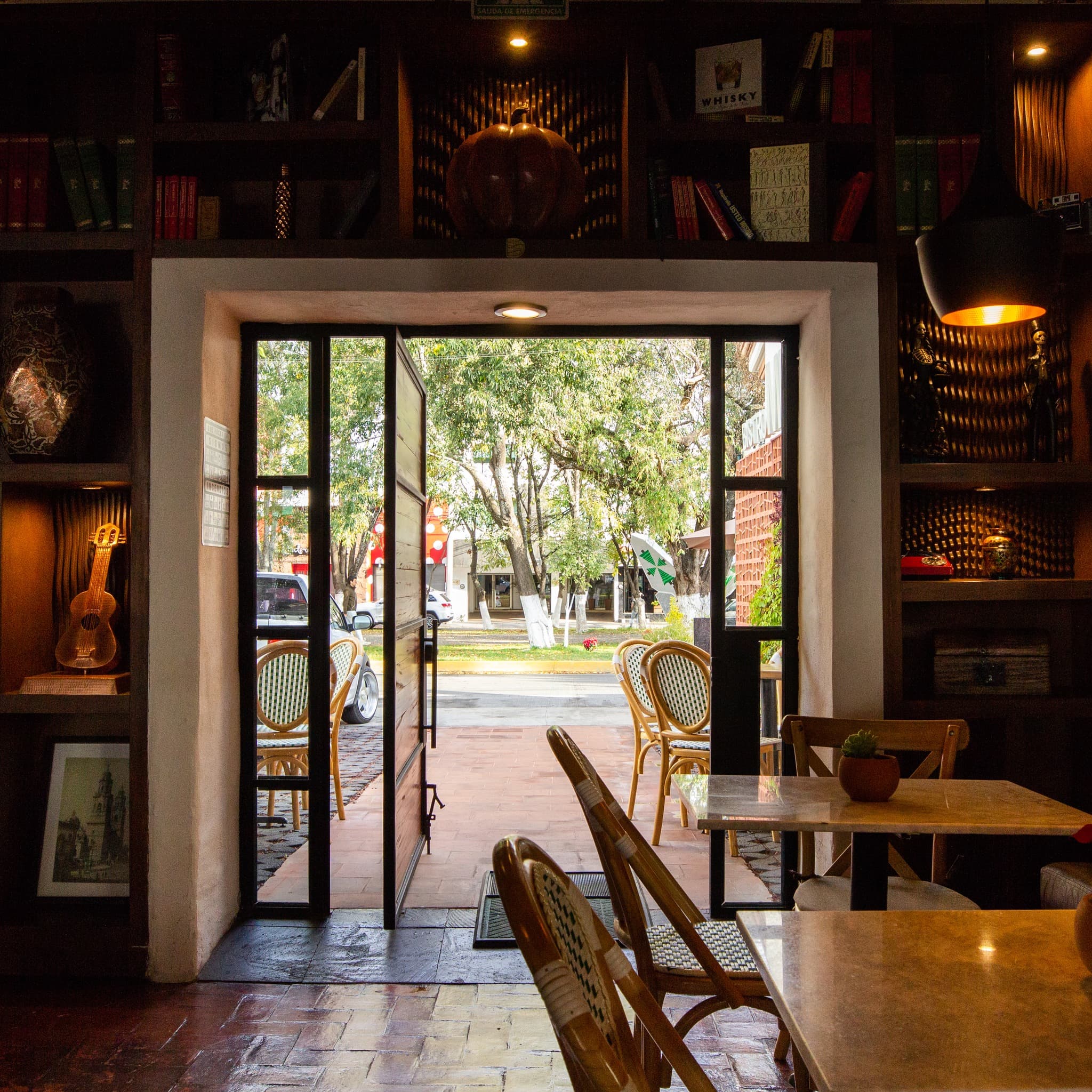 Interior del bistró con puerta abierta a la terraza arbolada